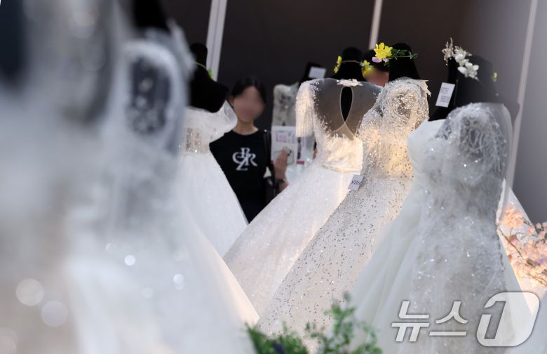지난달 6일 서울 강남구 삼성동 코엑스에서 열린 2025 추계 웨덱스 웨딩 박람회에서 예비 부부들이 전시된 드레스를 살펴보고 있다. 2025.7.6/뉴스1 ⓒ News1 김성진 기자
