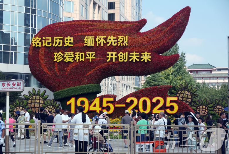 중국 인민 항일전쟁 및 세계 반파시스트 전쟁(제2차 세계대전) 승리 80주년(전승절) 기념 열병식을 사흘 앞둔 31일 중국 베이징 톈안먼(천안문) 인근 거리에 설치된 꽃 조형물 앞에서 행인들이 기념 사진을 찍고 있다. 2025.8.31/뉴스1 ⓒ News1 박정호 기자