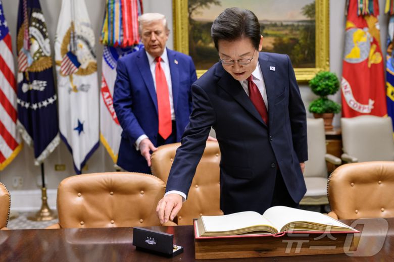 지난 8월 25일(현지시간) 이재명 대통령이 한미정상회담에 앞서 미 백악관 루즈벨트룸에서 방명록에 서명하려고 펜을 잡으려는 순간 도널드 트럼프 미국 대통령이 뒤에서 의자를 당겨 주고 있다. (백악관 제공. 재판매 및 DB금지) 2025.9.1/뉴스1 ⓒ News1