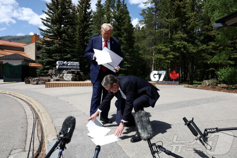 키어 스타머 영국 총리가 2025년 6월 16일 캐나다 앨버타주 캐내내스키스에서 열린 주요 7개국(G7) 정상회의 도중, 도널드 트럼프 미국 대통령이 기자들과 이야기하는 동안 떨어뜨린 서류를 주워주고 있다. 2025.6.16 ⓒ 로이터=뉴스1 ⓒ News1 강민경 기자