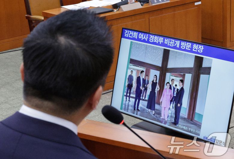 정용석 국립박물관문화재단 사장이 지난 22일 서울 여의도 국회 문화체육관광위원회에서 열린 국립중앙박물관 등에 대한 국정감사에서 김건희 여사와 이배용 전 국가교육위원장 등이 지난 2023년 9월 경복궁 경회루를 방문했을 때의 사진을 바라보고 있다. 당시 대통령실 문체비서관실 선임행정관으로 근무하며 경회루 방문에 동행한 정 사장은 이날 국감에서 김 여사가 근정전 용상에 스스로 1~2분 착석했다고 밝혔다. 2025.10.22/뉴스1 ⓒ News1 신웅수 기자