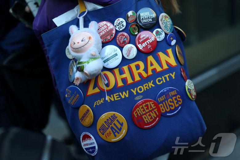 10월 27일(현지시간) 뉴욕 맨해튼 어퍼 이스트 사이드에서 조란 맘다니 민주당 뉴욕시장 후보가 사전투표 기간 중 선거 유세를 하는 가운데, 한 지지자가 맘다니를 지지하는 내용의 문구가 적힌 가방을 메고 이동하고 있다. 2025.10.27. ⓒ 로이터=뉴스1 ⓒ News1 윤다정 기자