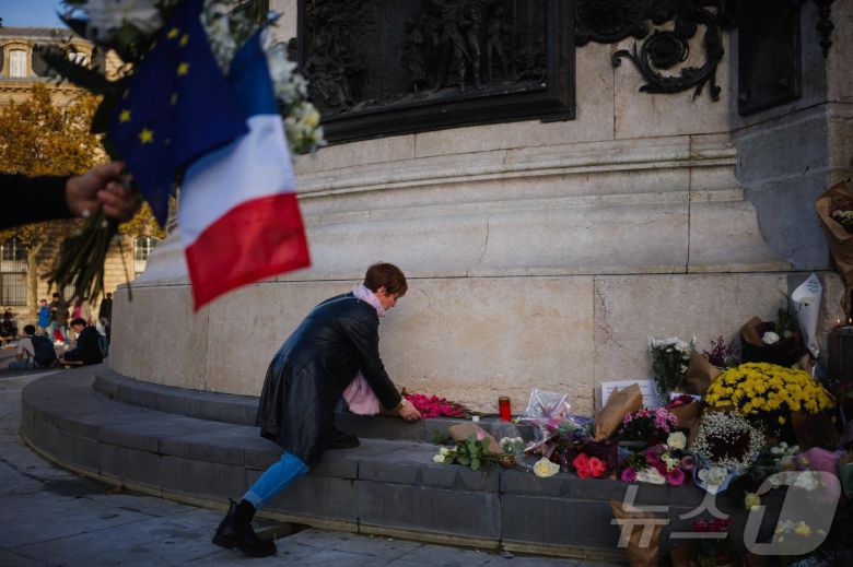 11일(현지시간) 파리 레퓌블리크 광장에 마련된 임시 추모비에서 한 여성이 테러 희생자들을 추모하며 꽃을 헌화하고 있다. 2025.11.11. ⓒ AFP=뉴스1 ⓒ News1 이정환 기자