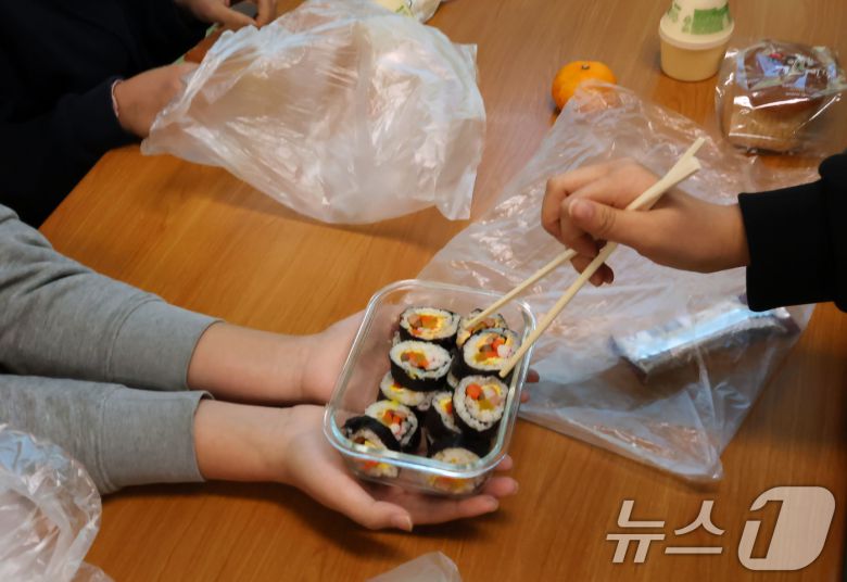 21일 학교비정규직 노조의 파업으로 인해 광주 북구 문흥동 문흥중학교에서 학생들이 대체식인 빵을 먹고 있다. 사진은 한 학생이 싸온 김밥을 친구들에게 나눠주는 모습. ⓒ News1 박지현 기자