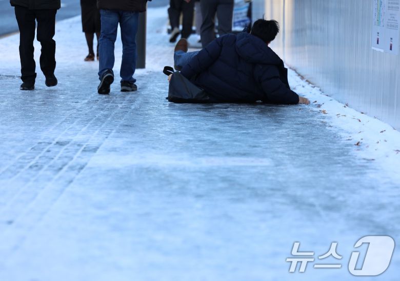 폭설 후 한파로 도로 곳곳이 얼어붙은 5일 오전 서울 광화문역 일대에서 한 시민이 빙판길에 미끄러져 넘어지고 있다. 2025.12.5/뉴스1 ⓒ News1 구윤성 기자