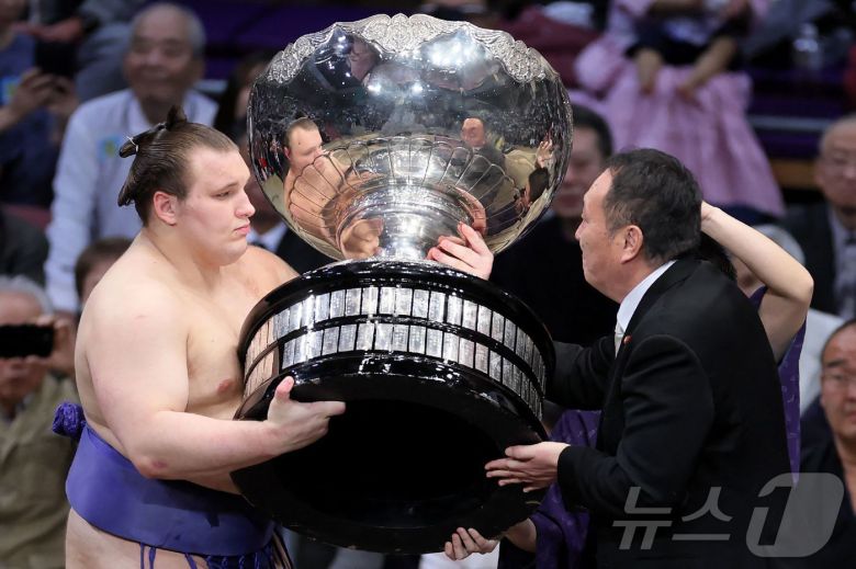 우크라이나 출신 스모 선수 다닐로 야브후시신(왼쪽, 일본식 이름은 아오니시키 아라타)가 후쿠오카에서 열린 일본 프로 스모 규슈대회에서 우승한 뒤 다카이치 사나에 일본 총리의 보좌관으로부터 총리배 트로피를 받고 있다. 2025.11.23.ⓒ AFP=뉴스1