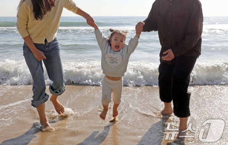 포근한 날씨를 보인 16일 부산 해운대해수욕장에서 가벼운 복장 차림을 한 가족이 바닷물에 발을 담그며 즐거운 시간을 보내고 있다. 2026.1.16/뉴스1 ⓒ News1 윤일지 기자
