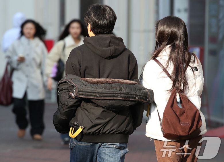 하루 사이 기온이 크게 오른 지난 15일 오후 대구 중구 동성로에서 한 시민이 외투를 반쯤 벗어 걸친 채 걸어가고 있다. 2026.1.15/뉴스1 ⓒ News1 공정식 기자