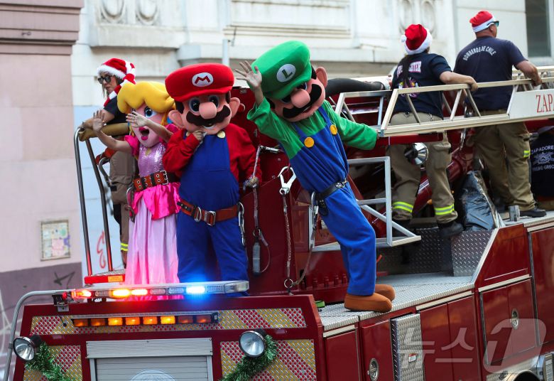 칠레 발파라이소에서 열린 크리스마스 축제에서 '슈퍼마리오' 캐릭터로 분장한 소방관들이 손을 흔들고 있다.2024.12.22 ⓒ 로이터=뉴스1 ⓒ 로이터=뉴스1