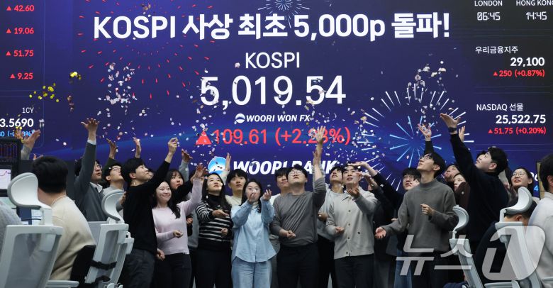 한국 증시가 사상 처음으로 '코스피 5000' 쾌거를 달성한 지난 22일 서울 중구 우리은행 본점 딜링룸에서 직원들이 장중 최고가가 찍힌 전광판을 배경으로 코스피 5000 돌파를 축하하고 있다. 2026.1.22/뉴스1 ⓒ News1 오대일 기자