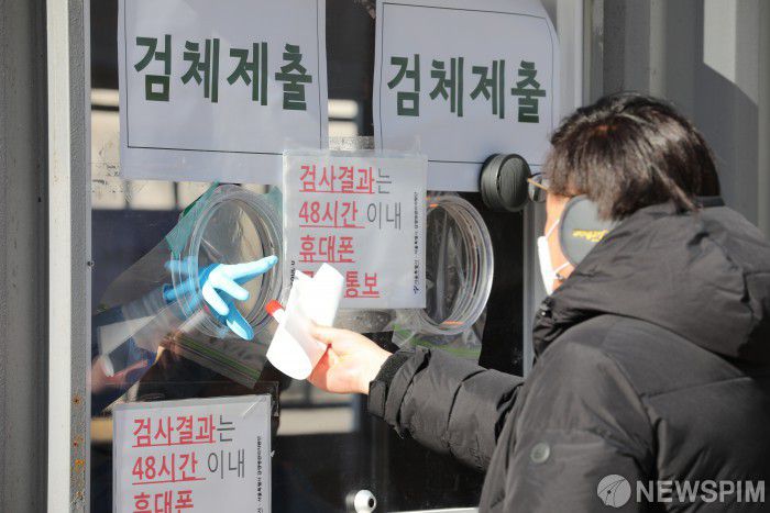 [서울=뉴스핌] 백인혁 기자 = '세밑한파'가 찾아온 30일 오전 서울 중구 서울시청 광장에 마련된 신종 코로나바이러스 감염증(코로나19) 임시 선별진료소에서 검사를 마친 한 시민이 검체를 제출하고 있다. 질병관리본부 중앙방역대책본부에 따르면 이날 0시 기준 국내 코로나19 신규 확진자는 1050명을 기록, 이틀째 1000명대를 이어갔다. 2020.12.30 dlsgur9757@newspim.com