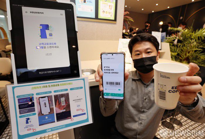 [서울=뉴스핌] 황준선 기자 = 6일 오후 서울 중구의 한 커피전문점에서 환경부 관계자가 오는 6월 10일부터 시행되는 1회용 컵 보증금제도 공개 시연을 하고 있다. 환경부는 이날 시연회에서 1회용 컵 보증금제 시행 후 소비자가 컵을 반납하고 자원순환보증금(300원)을 반환받는 과정을 홍보하고 점검했다. 2022.05.06 hwang@newspim.com