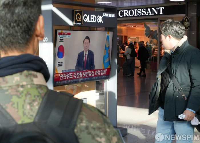 [서울=뉴스핌] 최지환 기자 = 12일 오전 서울 용산구 서울역에서 시민들이 윤석열 대통령의 긴급 성명 발표를 지켜보고 있다. 2024.12.12 choipix16@newspim.com