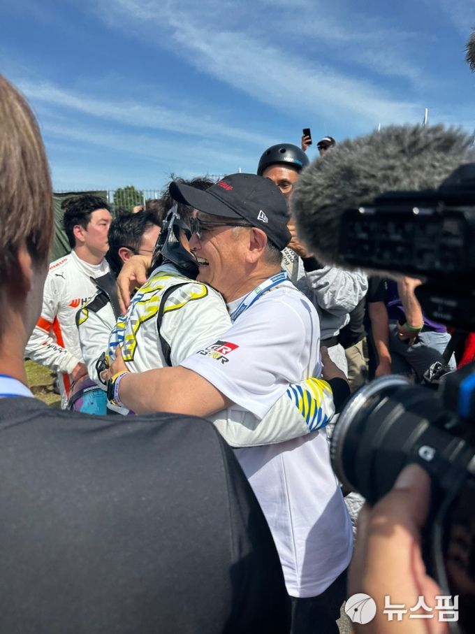 [뉘르부르크링(독일)=뉴스핌] 조수빈 기자 = 22일(현지시간) 뉘르부르크링 24시 내구 레이스 완주 이후 팀원들과 사진 촬영을 하고 있는 토요타 마스터 드라이버 모리조가 아들 토요다 다이스케 선수를 안아주고 있다. [사진=토요타 가주 루키레이싱 공동 취재단] 2025.06.22 beans@newspim.com