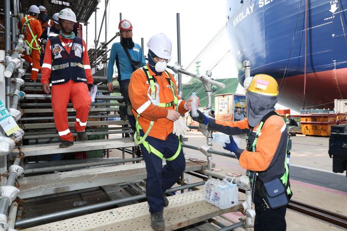 한화오션 안전관리자가 '찾아가는 얼음생수' 활동으로 오후 쉬는 시간 휴식을 위해 하선하는 작업자들에게 얼음 생수를 전달하고 있다. [사진=한화오션]