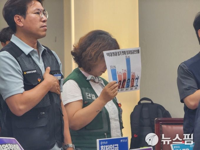 [세종=뉴스핌] 양가희 기자 = 10일 정부세종청사에서 열린 최저임금위원회 제12차 전원회의 시작에 앞서 국민의례가 진행되는 가운데 민주노총 소속 도명화 근로자위원(가운데)은 국기에 대한 맹세를 하지 않고 '역대 정권 임기 첫 해 최저임금인상률' 그래프가 인쇄된 종이를 들고 고개를 숙이고 있다. 2025.07.10 sheep@newspim.com