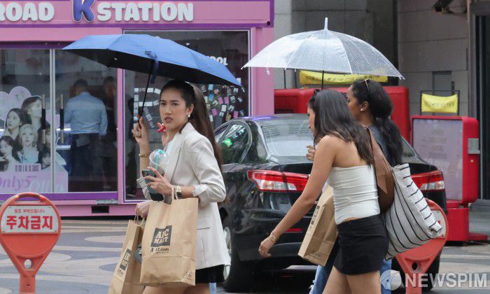 [서울=뉴스핌] 양윤모 기자 = 국정기획위원회가 6일 관광산업 활성화를 위해 일정한 요건을 갖춘 중국인 단체관광객의 한시적 무비자 입국 허용을 정부에 제안한 가운데, 비가 내리는 명동을 관광객들이 쇼핑을 위해 이동하고 있다. 2025.08.06 yym58@newspim.com