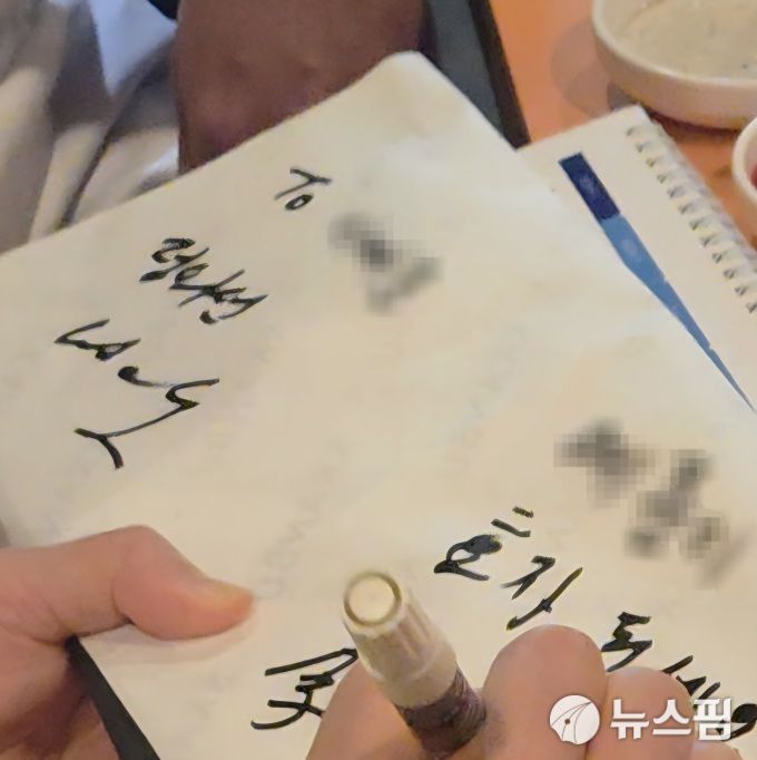 [서울=뉴스핌] 김아영 기자 = 이재용 삼성전자 회장이 지난 30일 서울 강남구 삼성역 인근 깐부치킨 매장에서 정의선 현대차그룹 회장, 젠슨 황 엔비디아 CEO와 함께한 치킨 회동에서 초등학생 요청에 사인을 하고 있는 모습. 2025.10.31 aykim@newspim.com 2025.10.31 aykim@newspim.com