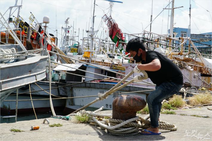 한 외국인 선원이 배를 항구 접안시설에 줄로 고정하고 있다.(사진=고상현 기자)