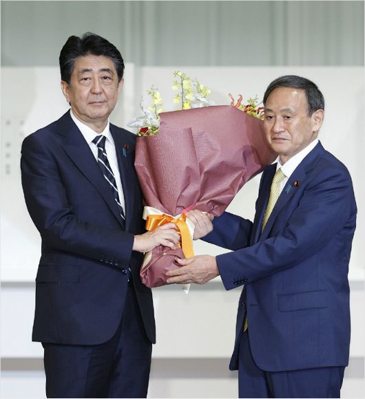 14일 총재 경선이 끝난 뒤 아베 신조(安倍晋三) 총리로부터 축하 꽃다발을 받는 스가 신임 자민당 총재(사진=연합뉴스)