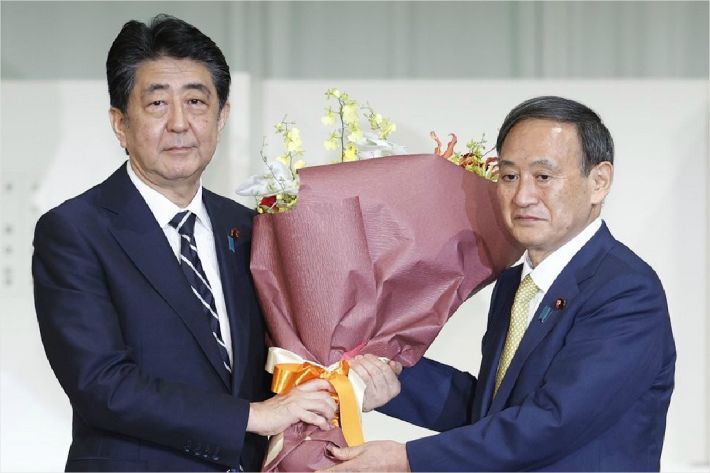지난 9월 14일 총재 경선이 끝난 뒤 스가 신임 자민당 총재로부터 꽃다발을 받는 아베 신조 총리. (사진=연합뉴스)