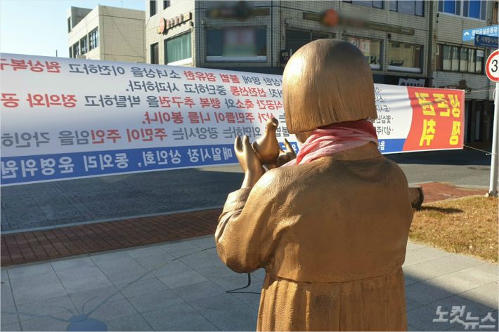 광양 평화의 소녀상이 인근 상인들의 이전 요구가 담긴 현수막을 바라보고 있다. (사진=최창민 기자)