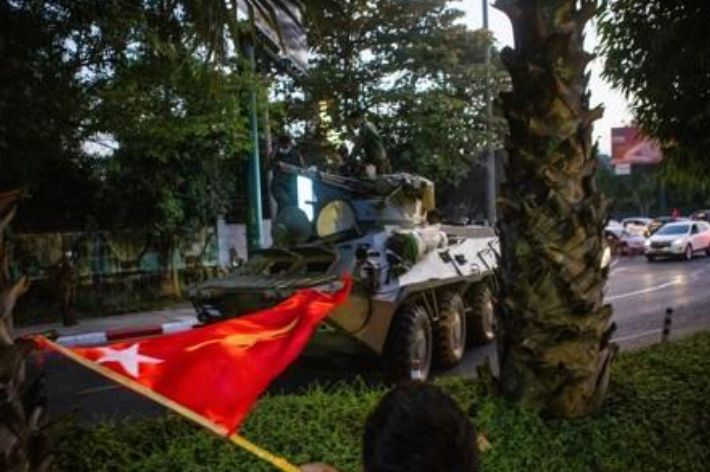 양곤 시내를 이동하는 장갑차 옆으로 한 시민이 깃발을 흔들고 있다. 연합뉴스