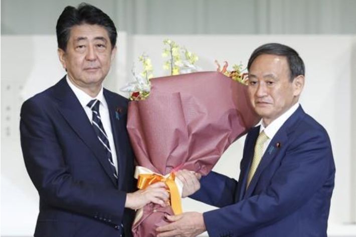 작년 9월 자민당 총재 경선에서 승리한 스가 요시히데(菅義偉) 일본 총리(당시 관방장관)가 물러나는 아베 신조 전 총리( 당시 총리)에게 꽃다발을 건네고 있다. 연합뉴스