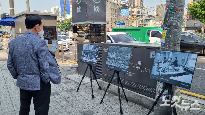 한 시민이 18일 오후 서울 관악구 서울대입구역 근처에서 열린 '5.18 민주화운동 사진전'에 전시돼 있는 사진을 보고 있다.  김정록 수습기자