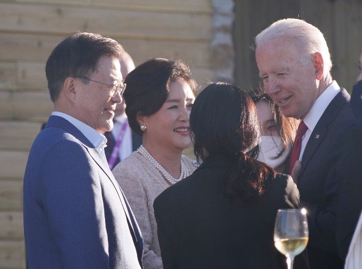 G7 정상회의에 참석 중인 문재인 대통령 부부와 조 바이든 미국 대통령이 12일 오후(현지시간) 영국 콘월 카비스베이 호텔 앞 해변에 마련된 만찬장에서 에어쇼를 기다리며 환담을 나누고 있다. 연합뉴스