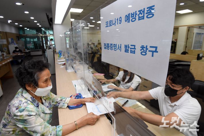 서울 양천구 신정1동 주민센터에서 어르신이 백신 접종증명서와 스티커를 받고 있다. 황진환 기자