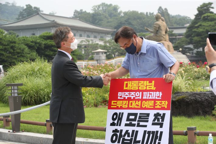 국민의힘 대권주자인 최재형 전 감사원장(왼쪽)이 29일 오전 서울 종로구 청와대 사랑채 앞에서 '드루킹 댓글 사건' 관련 1인 시위를 벌이고 있는 국민의힘 정진석 의원을 지지 방문해 악수하고 있다. 연합뉴스