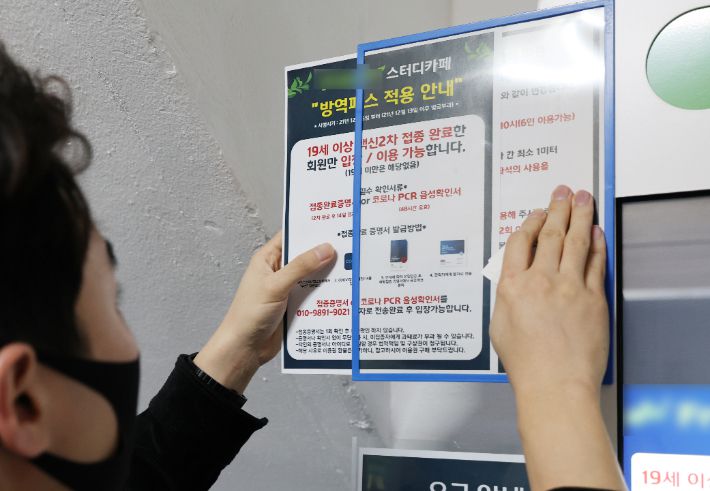 법원이 학원 및 독서실 등 교육시설에 대한 방역패스 효력 정지 결정을 내린 지난 4일 서울 시내의 한 스터디카페에서 관계자가 방역패스 안내문을 제거하고 있다. 연합뉴스