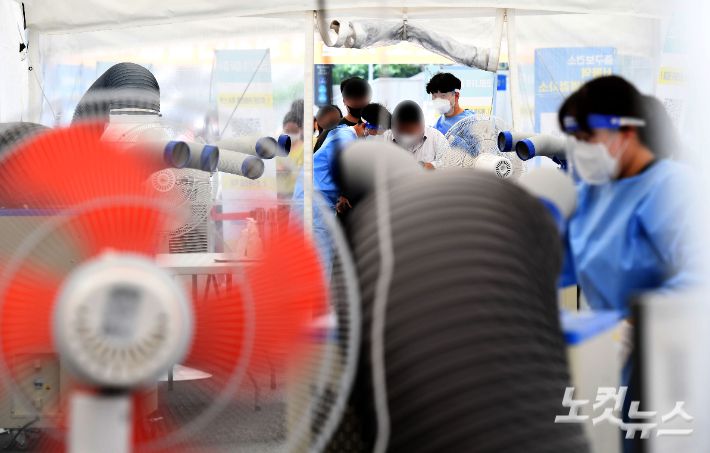 지난 3일 서울역광장에 마련된 임시선별검사소에서 의료진이 냉풍기와 대형 선풍기로 덕위를 식히고 있다. 황진환 기자