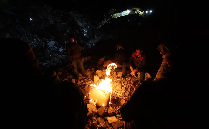 지난 8일 오후(현지시간) 튀르키예 이스켄데룬 시내의 지진 구조작업 현장에서 구조대와 시민들이 모닥불을 쬐며 추위를 녹이고 있다. 연합뉴스