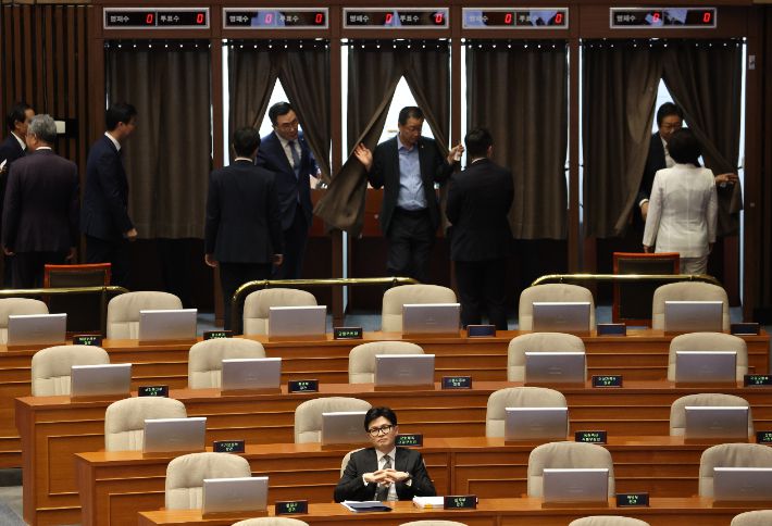 한동훈 법무장관이 21일 국회 본회의장에서 더불어민주당 이재명 대표 체포동의안에 대한 투표를 하고 나오는 야당 의원들 앞에 앉아 있다. 연합뉴스