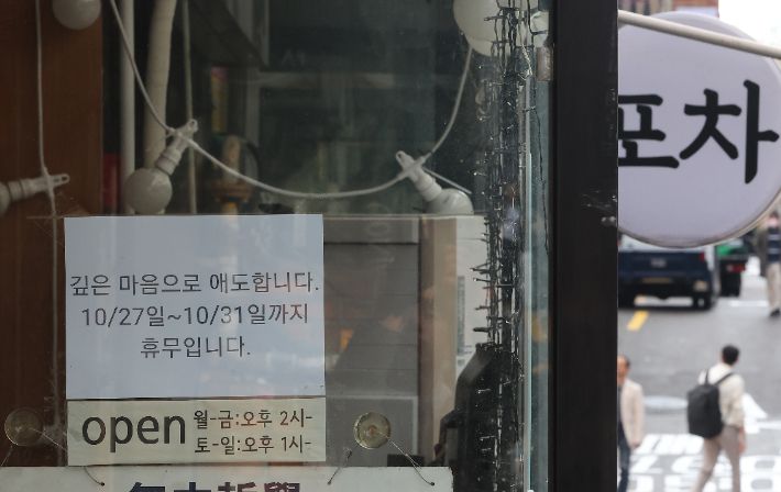 핼러윈 데이를 앞두고 시내 번화가에 인파 밀집이 예상되는 가운데 27일 오후 서울 용산구 이태원 거리 한 상점에 지난해 이태원 참사 희생자 추모 및 휴무 안내문이 붙어 있다. 연합뉴스