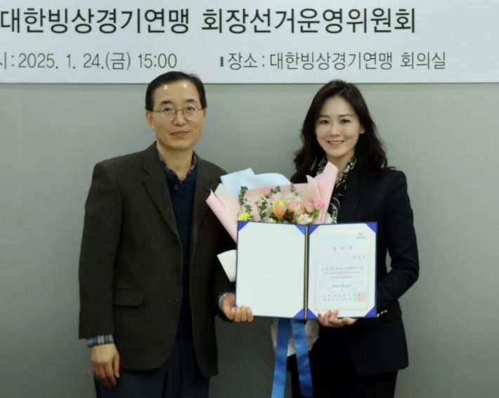 이수경(오른쪽) 삼보모터스 그룹 사장이 24일 서울시 송파구 대한빙상경기연맹 회의실에서 문성배 선거운영위원회 위원장으로부터 회장 당선증을 받은 뒤 밝게 웃고 있다. 대한빙상경기연맹