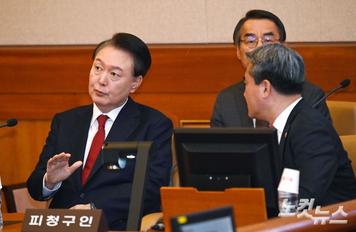 윤석열 대통령이 6일 오전 서울 종로구 헌법재판소 대심판정에서 열린 탄핵심판 6차 변론기일에 출석해 변호인단과 대화를 나누고 있다. 사진공동취재단