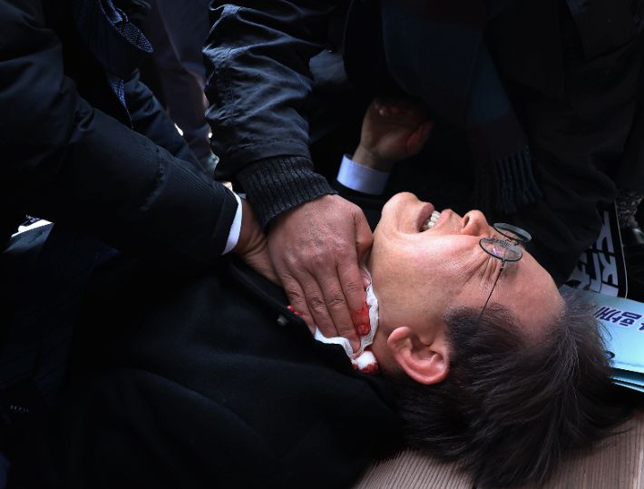 2024년 1월 2일 부산 가덕도 신공항 부지를 둘러본 후 기자들과 문답을 진행하던 중 왼쪽 목 부위를 습격당해 피를 흘린 채 쓰러진 모습. 연합뉴스