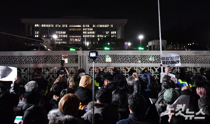 지난해 12월 4일 새벽 서울 여의도 국회의사당 정문 앞에서 군·경찰과 대치하던 시민들이 비상계엄 해제 요구 결의안이 가결되자 환호하고 있다. 류영주 기자
