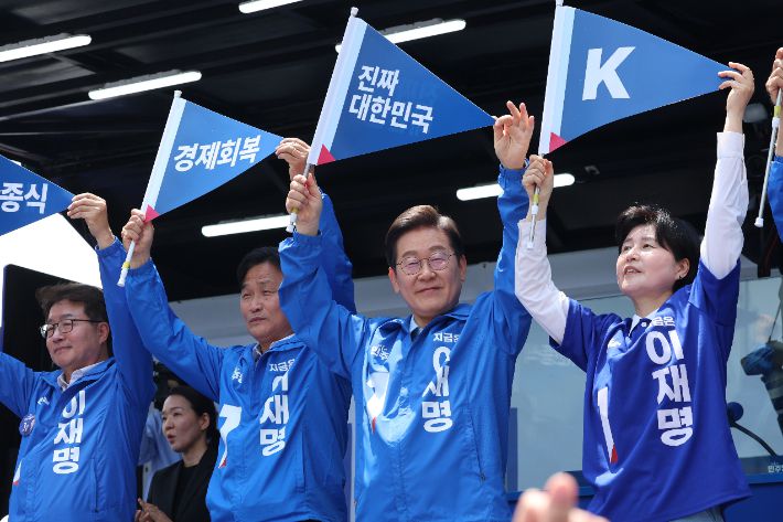 더불어민주당 이재명 대선 후보가 26일 수원시 팔달구 팔달문 영동시장에서 열린 집중 유세에서 "진짜 대한민국"이라고 쓰인 손깃발을 들고 인사하고 있다. 연합뉴스
