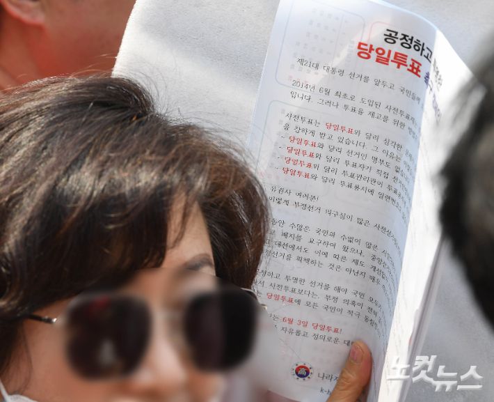 28일 오후 부산 진구 쥬디스태화 백화점 앞에서 진행된 국민의힘 김문수 대선 후보 유세현장에 한 시민이 '당일투표 촉구 캠페인' 인쇄물을 들고 있다. 부산=황진환 기자