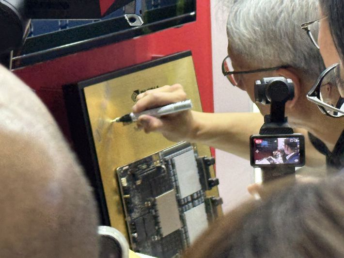 젠슨 황 엔비디아 CEO가 대만 타이베이 난강 전시관에서 개최된 '컴퓨텍스 2025'에서 SK하이닉스 부스를 찾아 전시된 HBM4에 사인하는 모습. 연합뉴스