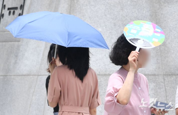 전국 곳곳에 폭염특보가 내려진 가운데 시민들이 양산과 부채를 들고 햇빛을 피하고 있다. 류영주 기자