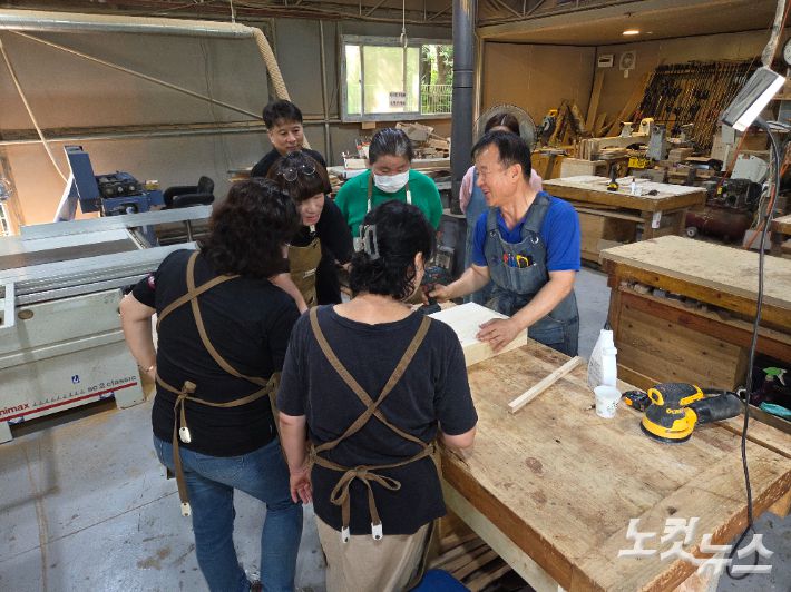목공소에서 교육을 맡고 있는 '미지 아빠' 유해종(65·사진 오른쪽)씨가 지난 22일 수강생들에게 강의를 하고 있다. 정성욱 기자