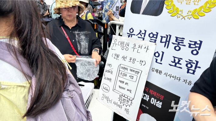 15일 서울역 광장에서 열린 '광화문 국민대회'에서 윤석열 전 대통령의 친필 싸인 책을 판매하는 윤 전 대통령 지지자들의 모습. 박인 기자