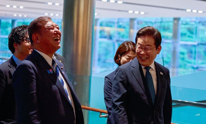 이재명 대통령이 23일 일본 도쿄 총리 관저에 도착해 이시바 시게루 일본 총리와 대화하며 이동하고 있다. 연합뉴스