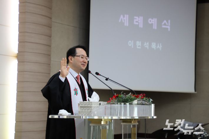 세례예식 집례하고 있는 이헌석 담임목사. 김일현 선교국장