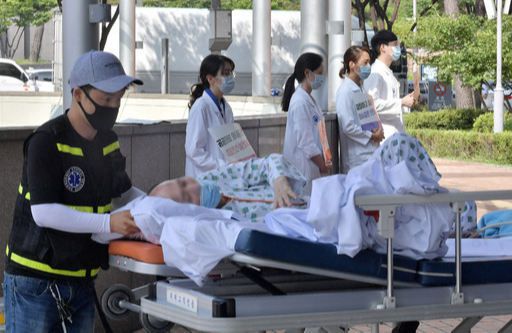 청진기 대신 피켓 든 의사들 의사들이 집단 휴진한 26일 서울 서초구 서울성모병원 입구에서 한 환자가 시위 중인 의사들 옆을 지나 이송되고 있다. 하상윤 기자